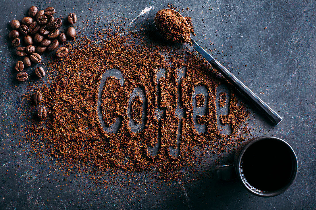 Coffee beans and ground coffee on dark background with the word Coffee written on it