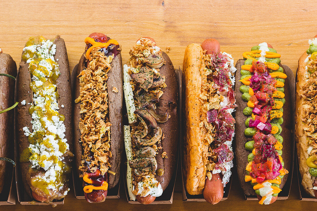 Row of assorted hot dogs with different delicious toppings and fillings