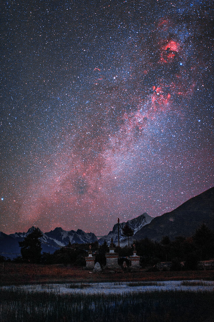 Milky Way and nebulae over mountain valley in Tibet