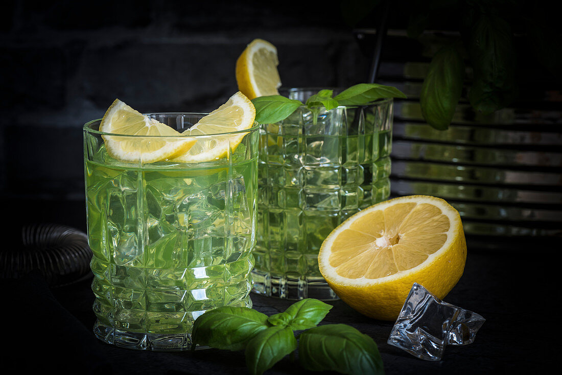 Gin Basil Smash cocktails with basil leaves and lemon in tumblers