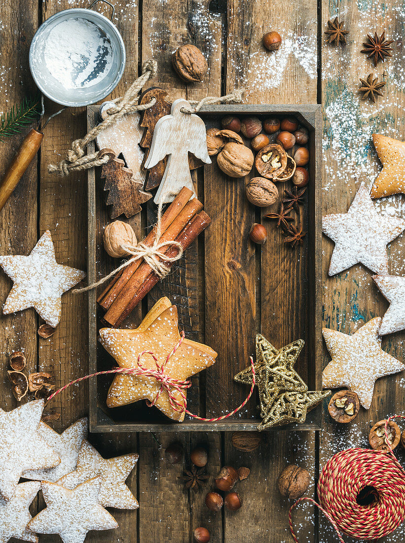 Gingerbread star shaped cookies, wooden angels, decorative stars, nuts and spices in wooden tray