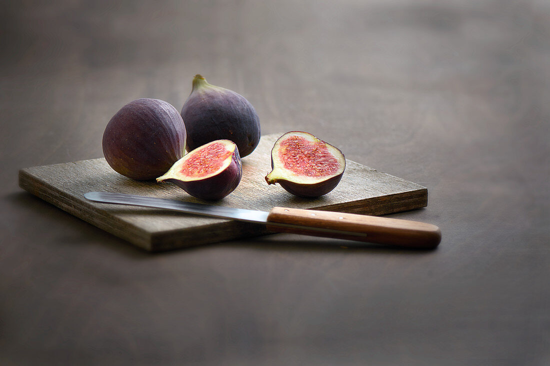 Frische Feigen auf Holzbrett mit Obstmesser