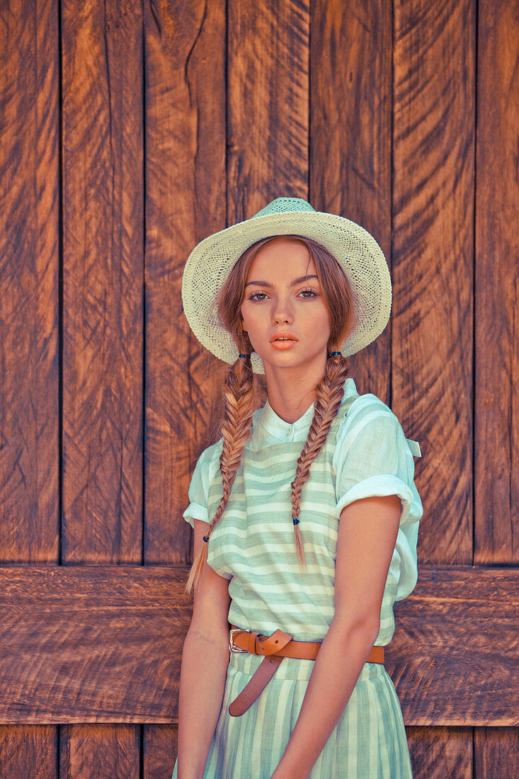 Junge Frau mit Hut in Bluse und gestreiftem Kleid