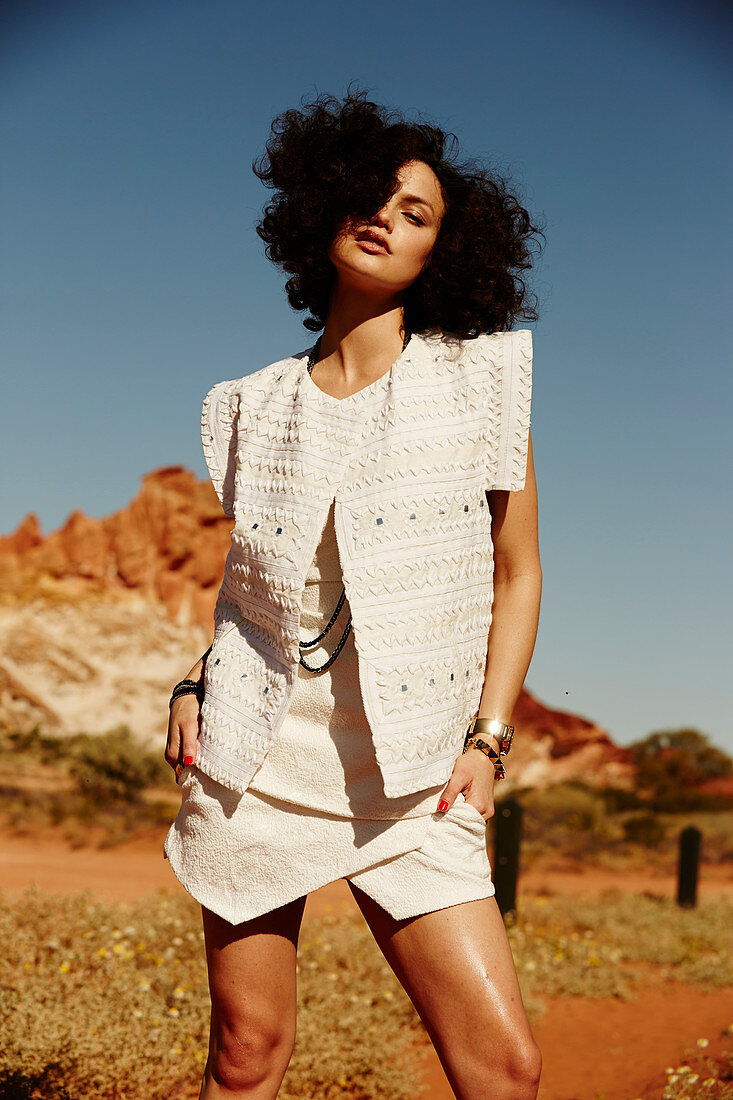 A young woman in the desert wearing a sleeveless waistcoat and a matching skirt