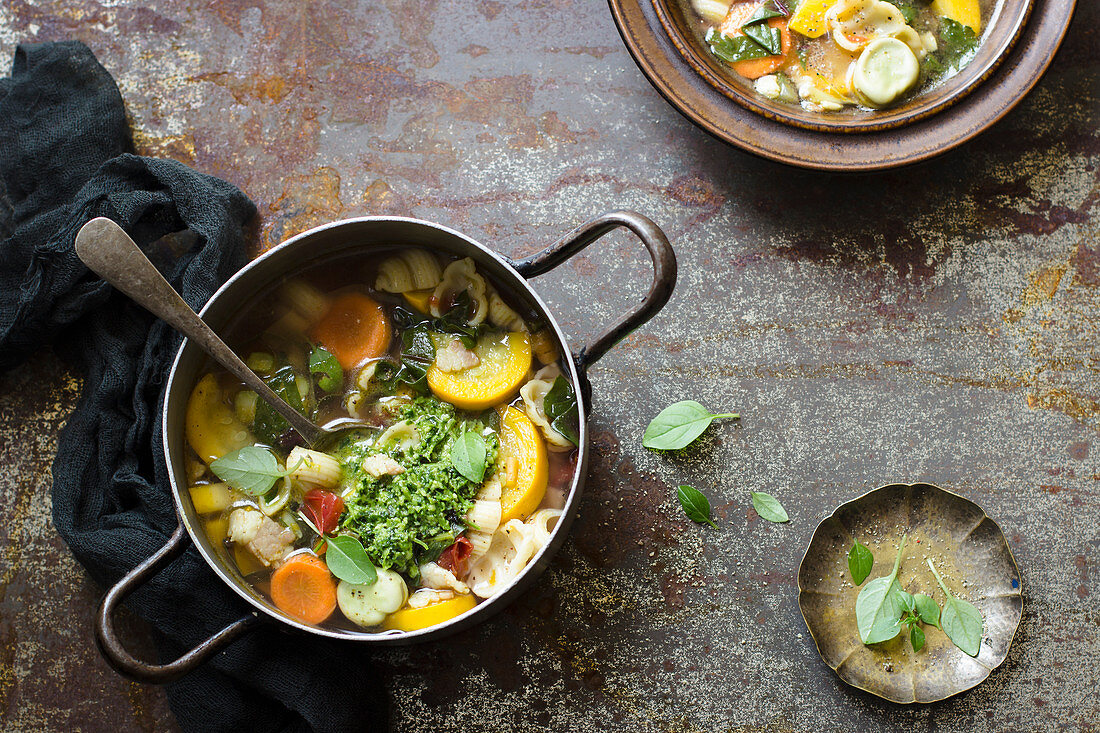 Summer minestrone soup with squash, carrot, tomatoes, basil pesto, broad bean and pasta shells