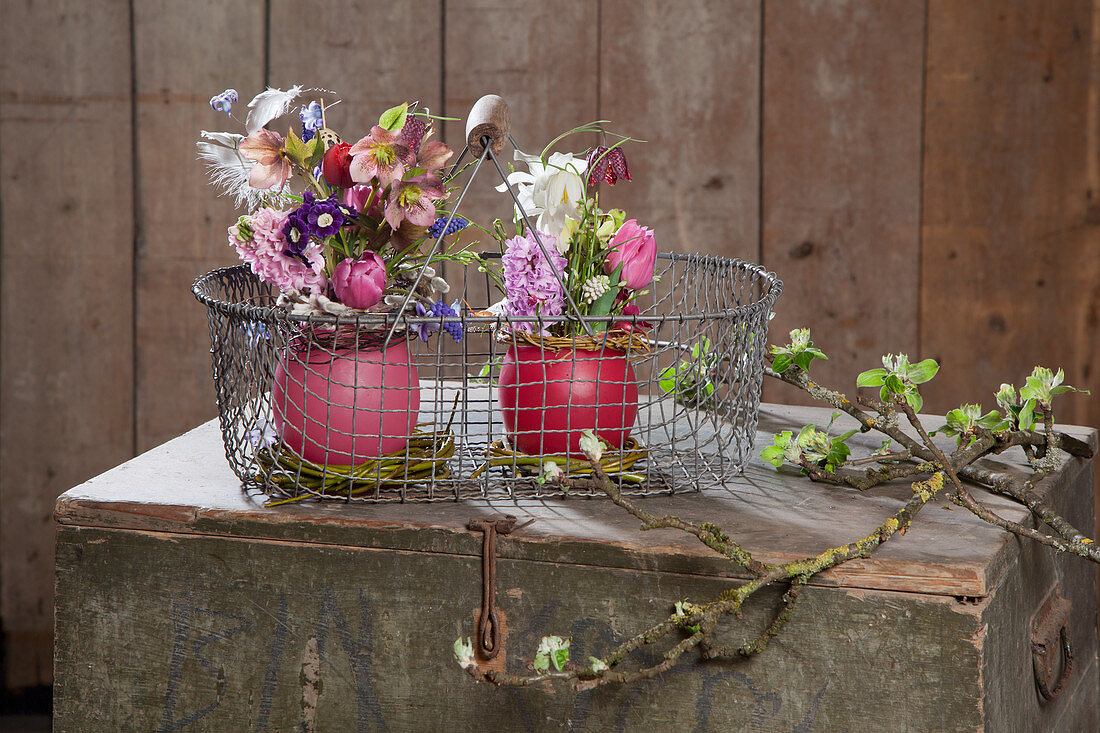 Spring flowers in wax vases in wire basket