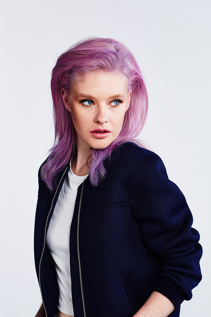 A young woman with pink hair wearing a white t-shirt and a dark-blue jacket