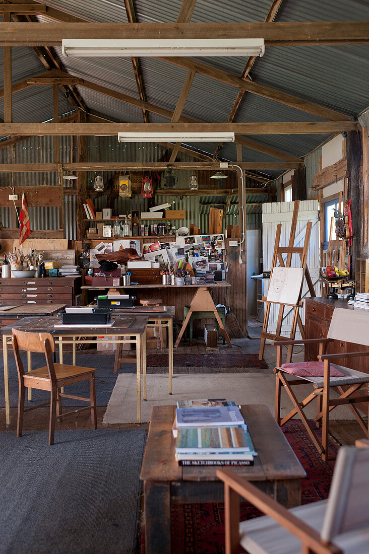 Atelier mit Holztischen in einer Scheune mit Wellblechdach