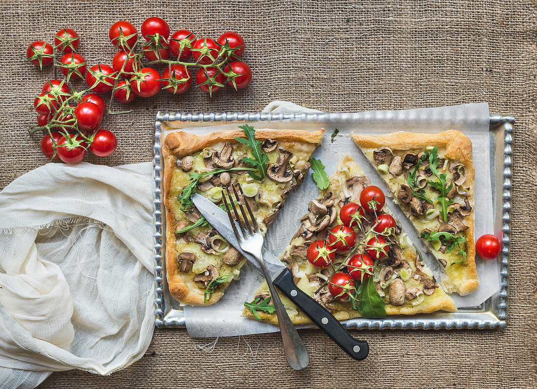 Ristic mushroom (fungi) square pizza with cherry tomatoes and arugula over a sackcloth background