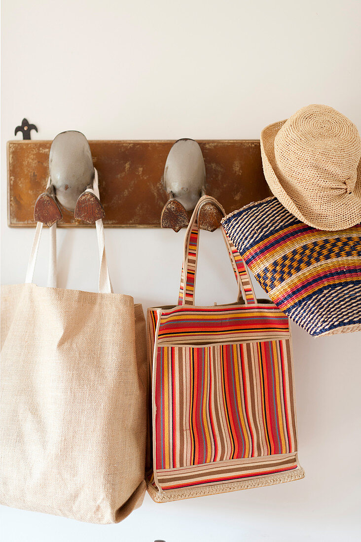 Summer hat, basket and bags hung from coat rack with ducks' feet