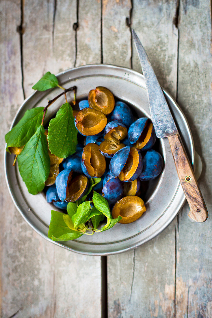 Damsons with leaves on a pewter plate