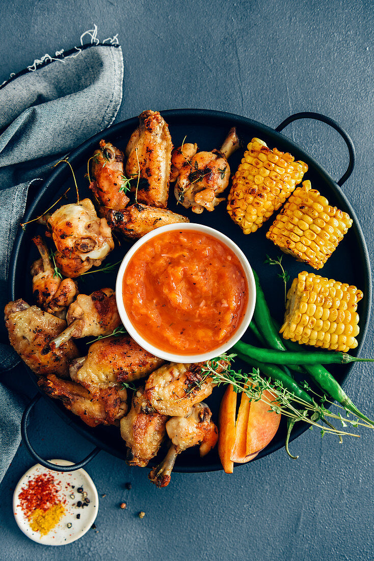 Gegrillte Chicken Wings und Maiskolben serviert mit zuckerfreier BBQ-Sauce