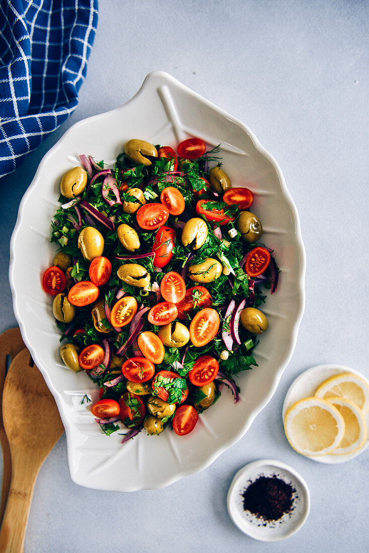 Salat mit grünen Oliven, Tomaten, Kräutern, Zwiebeln und Granatapfelsirup