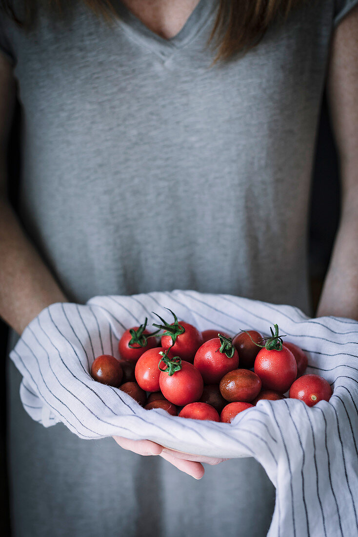 Frau hält frische Tomaten in Tuch gehüllt