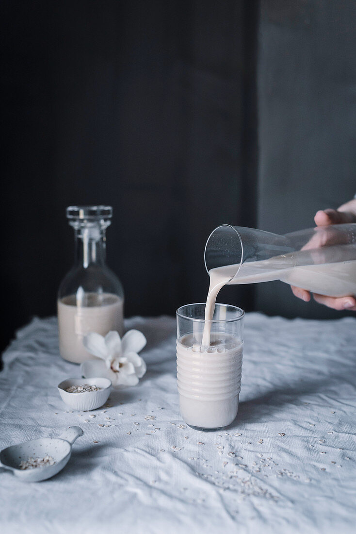 Selbstgemachte Haferdrink wird aus Karaffe in Glas gegossen