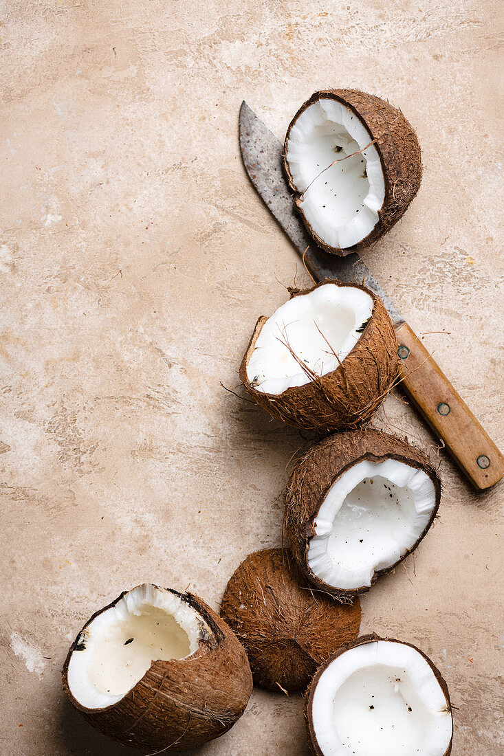 Drei frische halbierte Kokosnüsse mit Messer (Aufsicht)