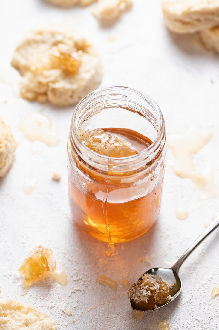 Ein Glas Honig mit Honigwabe, drumherum Buttermilch-Scones