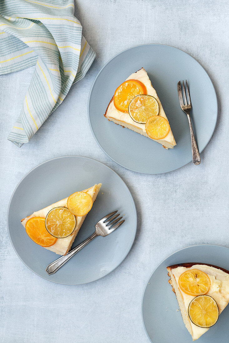 Slices of iced orange cake on plates with forks