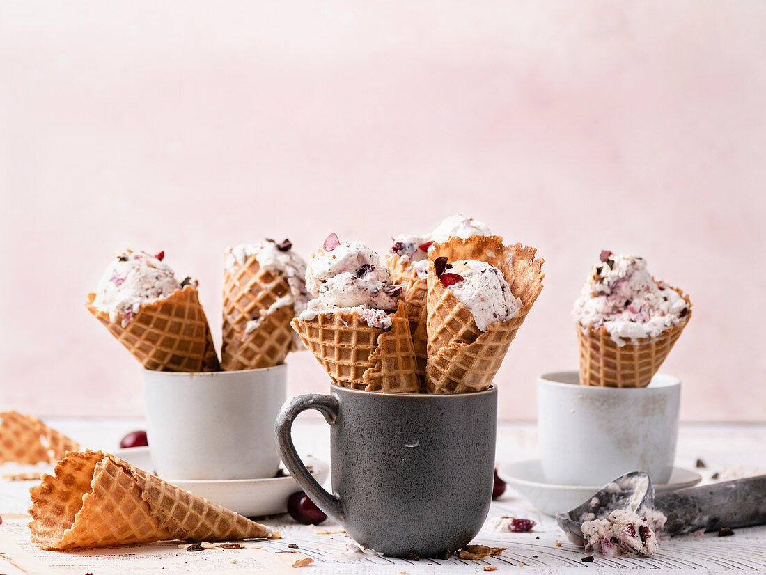 No churn vanilla ice cream with dark chocolate and cherry chunks in waffle cones
