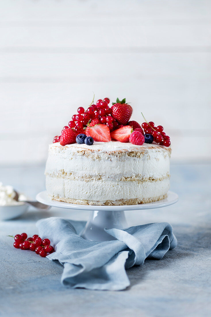 A naked cake with raspberries, strawberries, redcurrants and blueberries