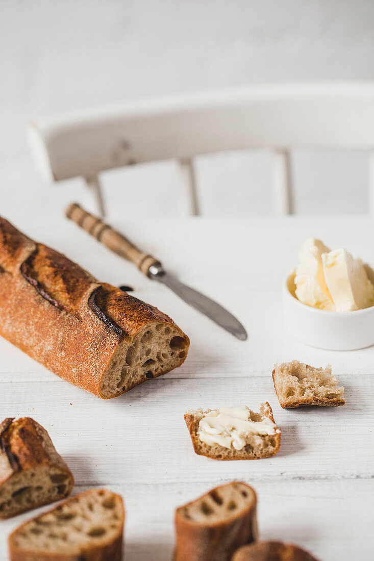 A sliced baguette with butter on a rustic kitchen table