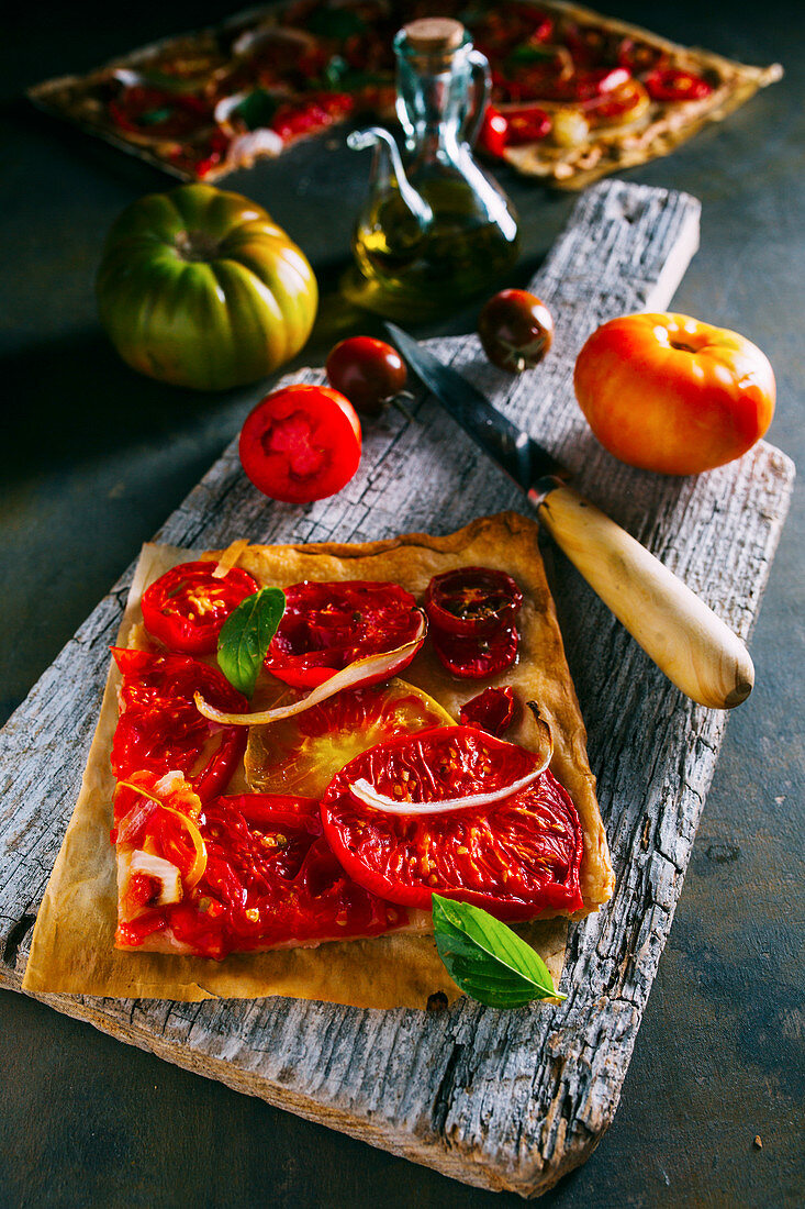 Tomato tart with onion and basil over puff pastry