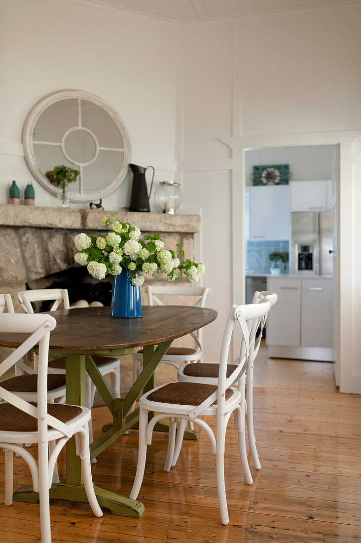 Oval wooden table and chairs in front of stone wall in dining room