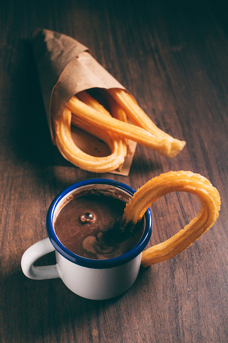 Churros (Spritzgebäck, Spanien) in Papiertüte mit Schokoladensauce in Emailletasse