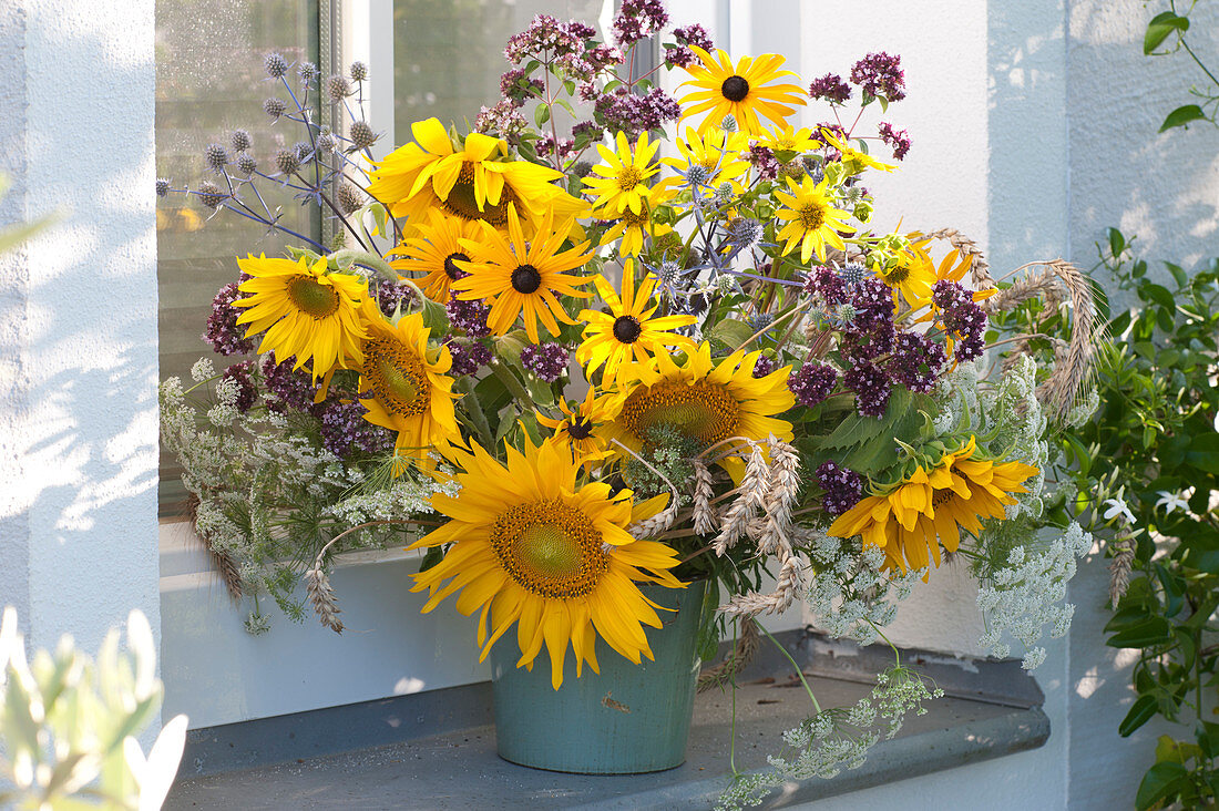 Thanksgiving bouquet with sunflowers, oregano and ears of wheat at the window