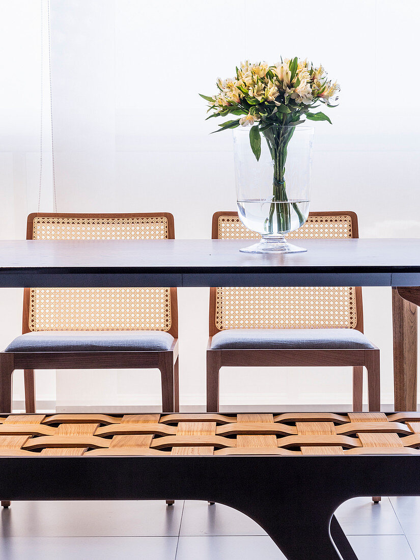 Table, bench and chairs with flowers in glass vase