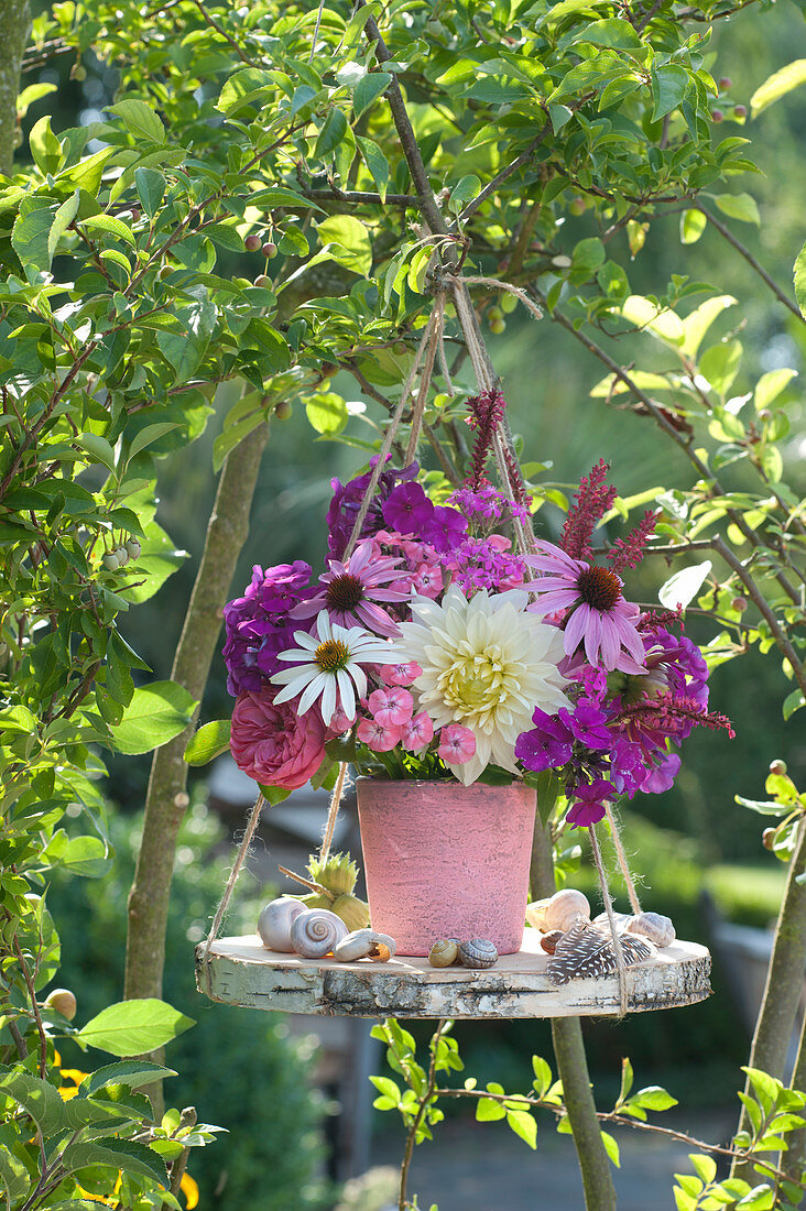 Bouquet of dahlia, coneflower, flame flowers and knotweed on a wooden disc