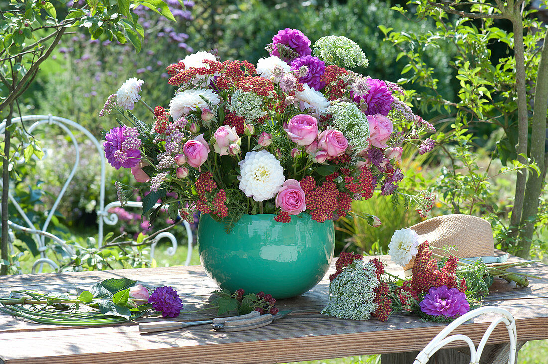 Üppiges Tischgesteck aus Rosen, Dahlien, Knorpelmöhre und Schafgarbe