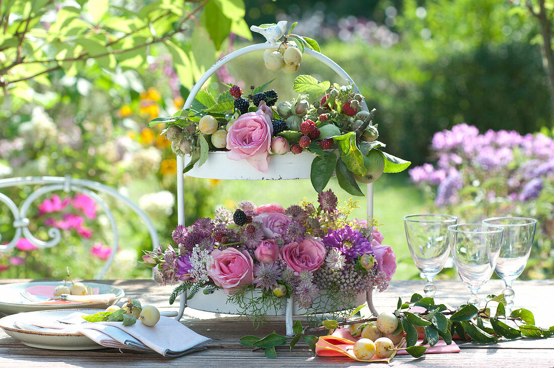 Romantic table decoration with roses, sterling flowers, dahlias and fruits on the floor