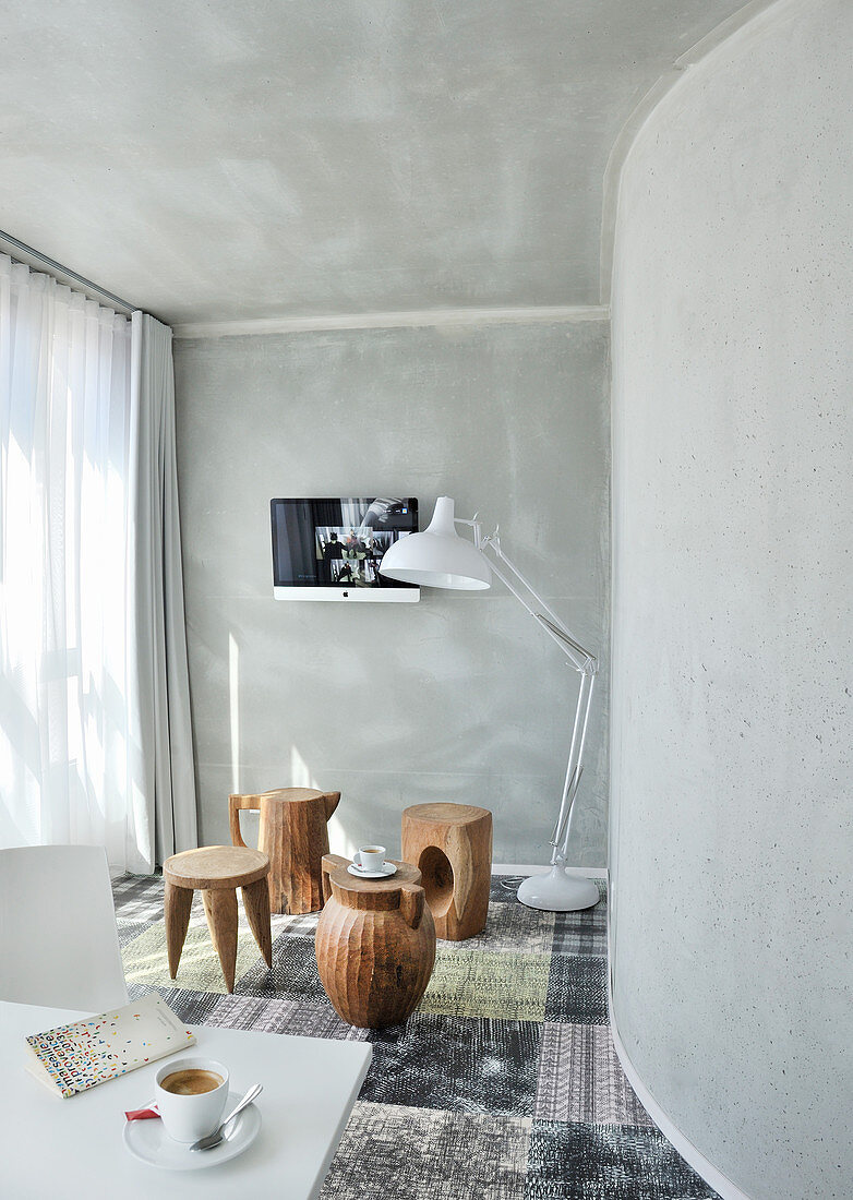 Baumstamm-Hocker in verschiedenen Formen und Stehleuchte im Zimmer mit grauen Wänden