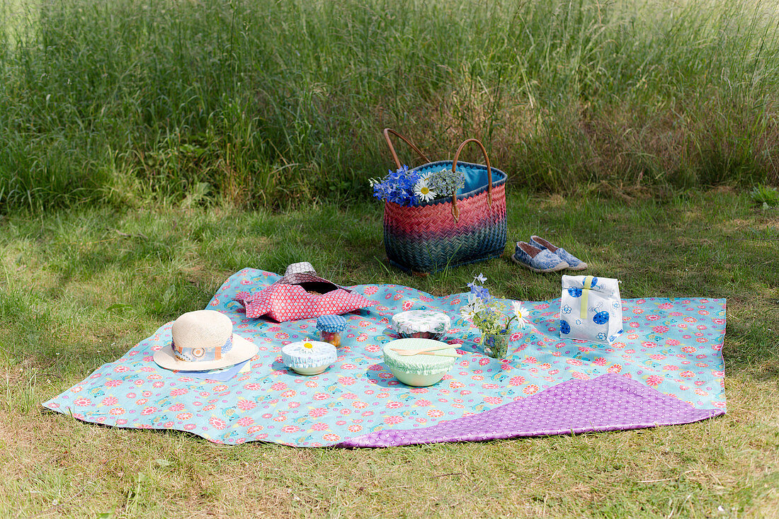 Schälchen mit Deckel, Kuchen in Kuchentasche und Lunchbag auf Picknickdecke aus Wachstuch