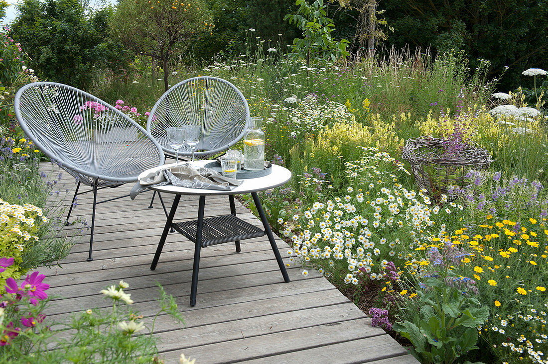 Small seating area on a wooden terrace in a flower meadow