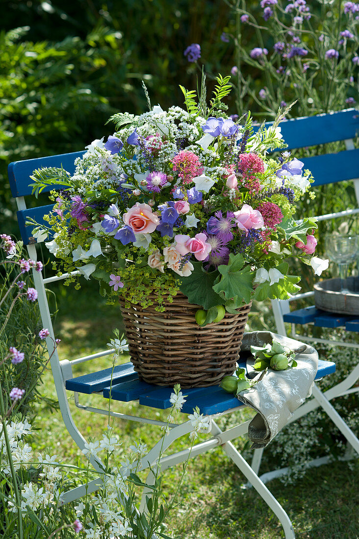 Lush summer bouquet of roses, shrubs and meadow flowers in a basket