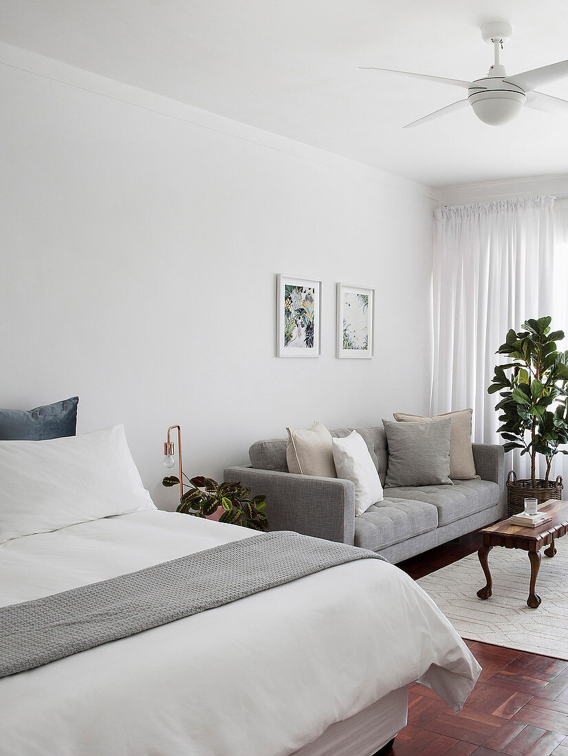 Schlafbereich mit Doppelbett und graues Polstersofa in offenem Wohnraum
