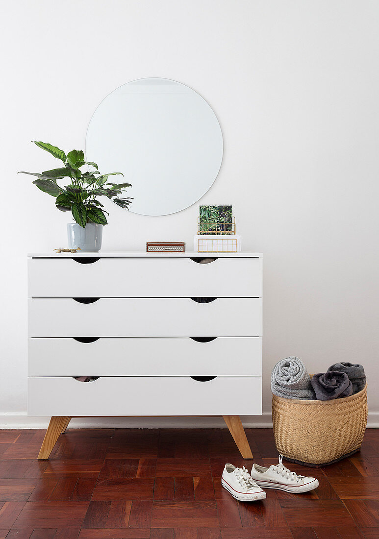 Houseplant on white chest of drawers below mirror on wall