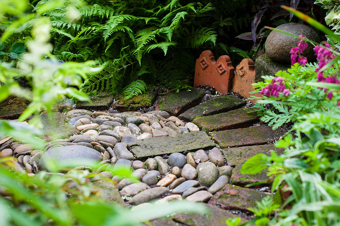 Kreisförmig angeordnete Kiesel und Backsteine im Garten