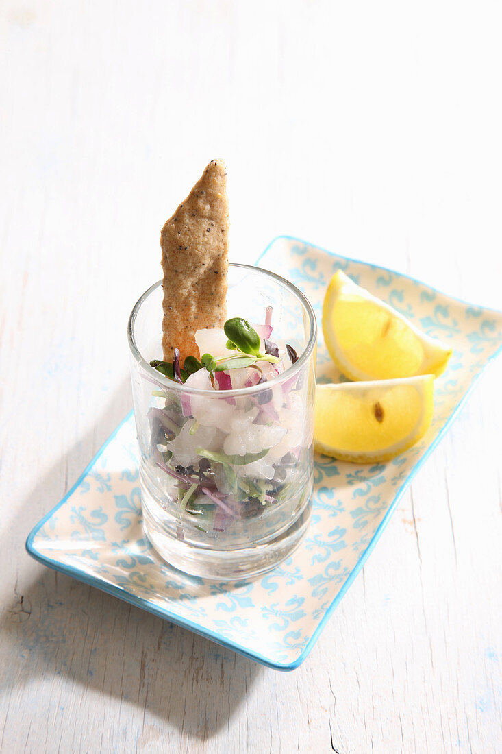 Ceviche served in a glass with crackers and lemon wedges