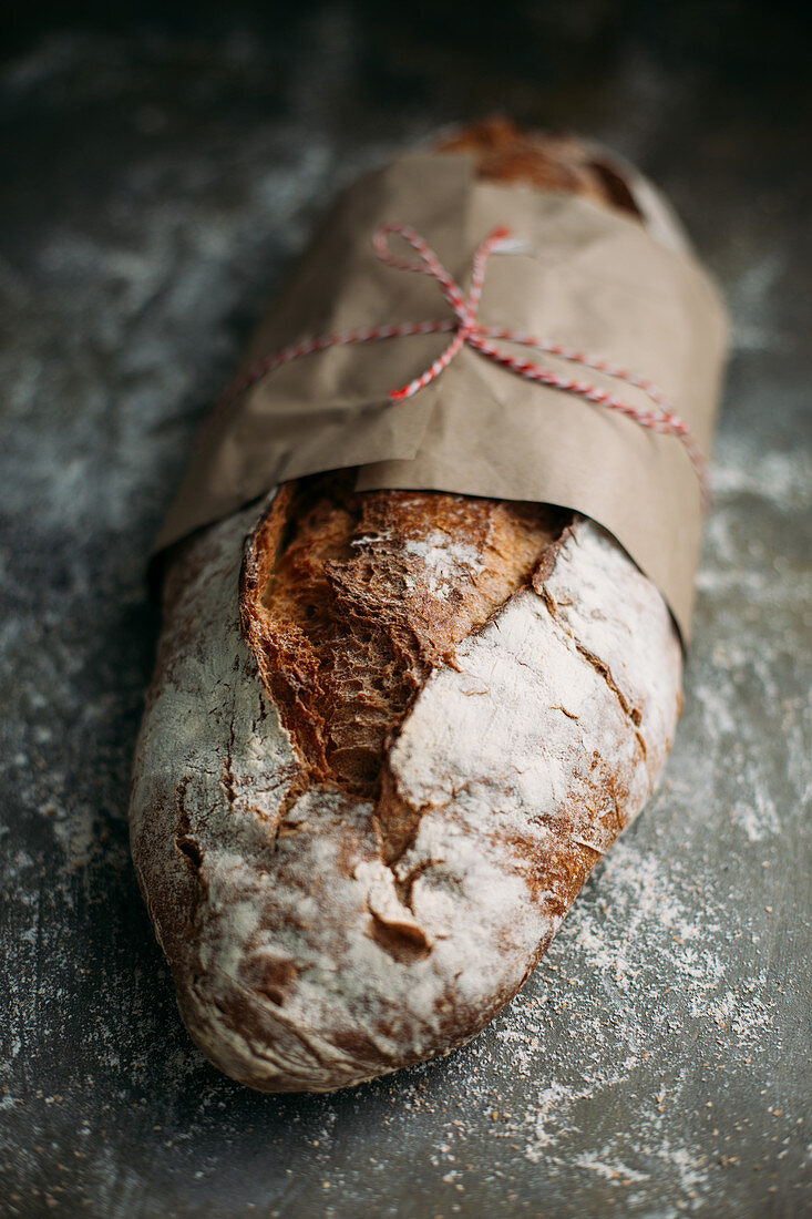 Rustikaler Brotlaib, mit Papier umwickelt