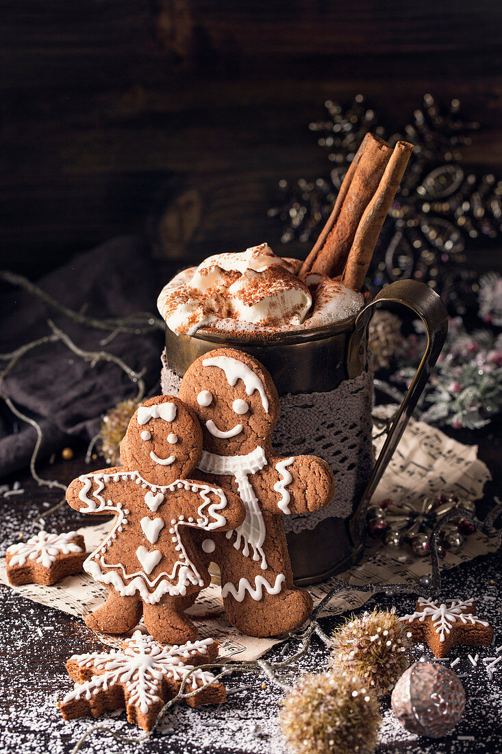 Hot chocolate with whipped cream and cinnamon stick and homemade gingerbread biscuits