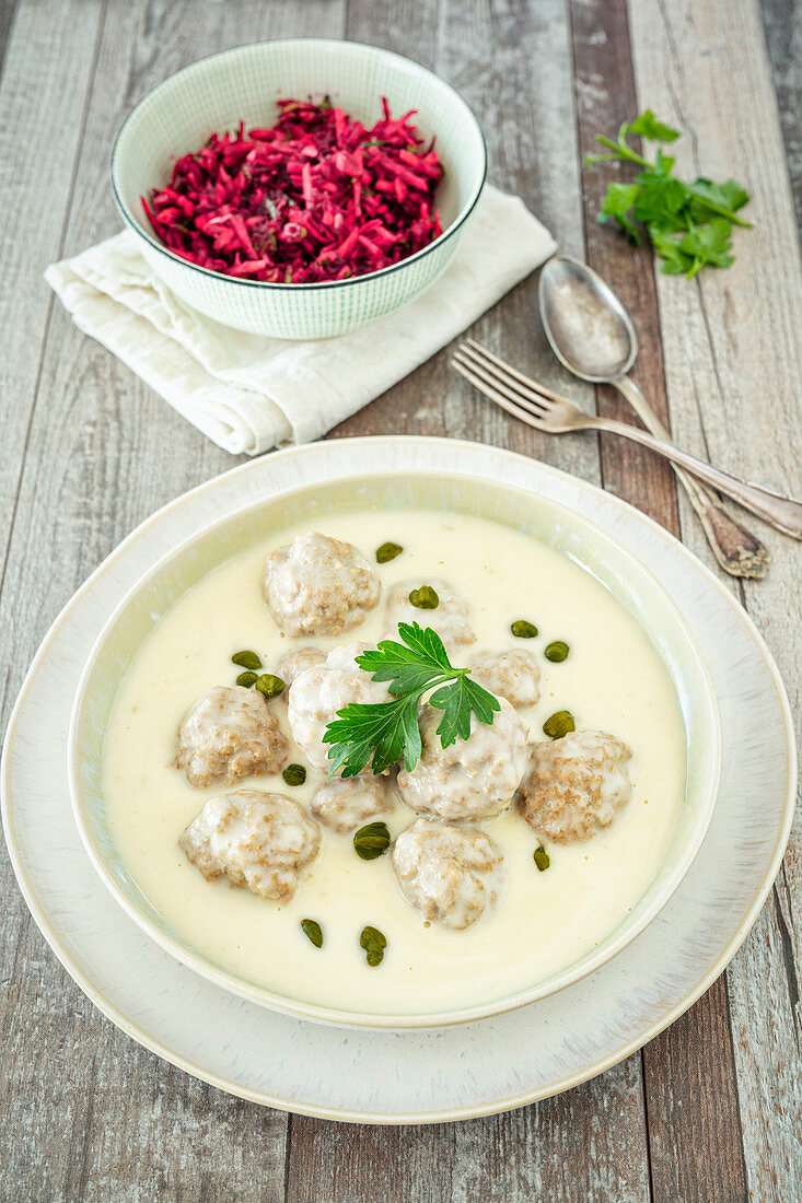 Meatballs in a white sauce with capers served with a beetroot and apple salad