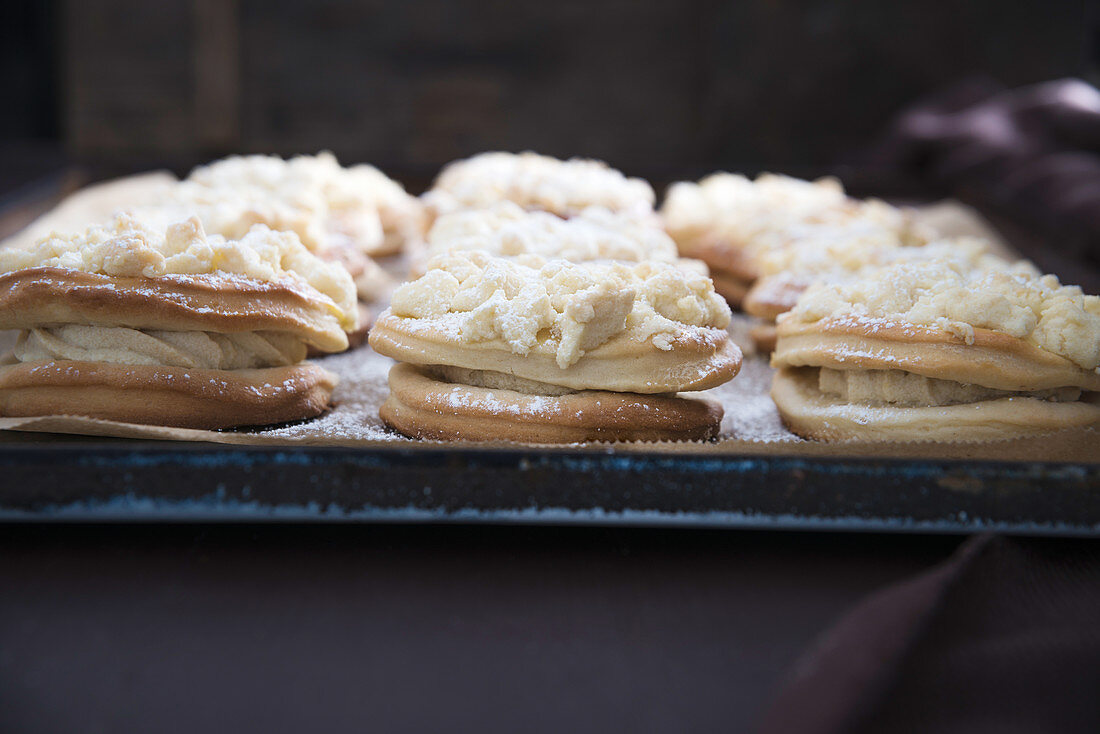 Vegan crumble cakes filled with pudding cream on a baking tray