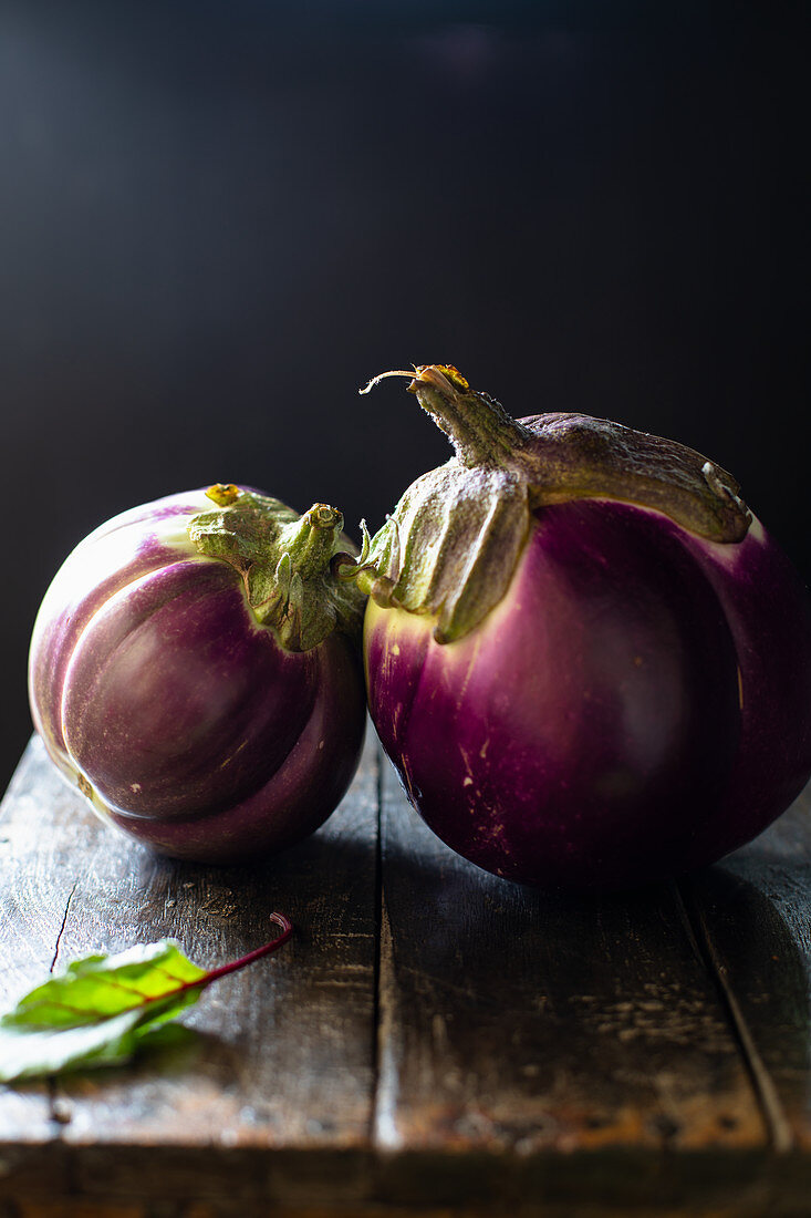 Two round eggplants on a wooden table