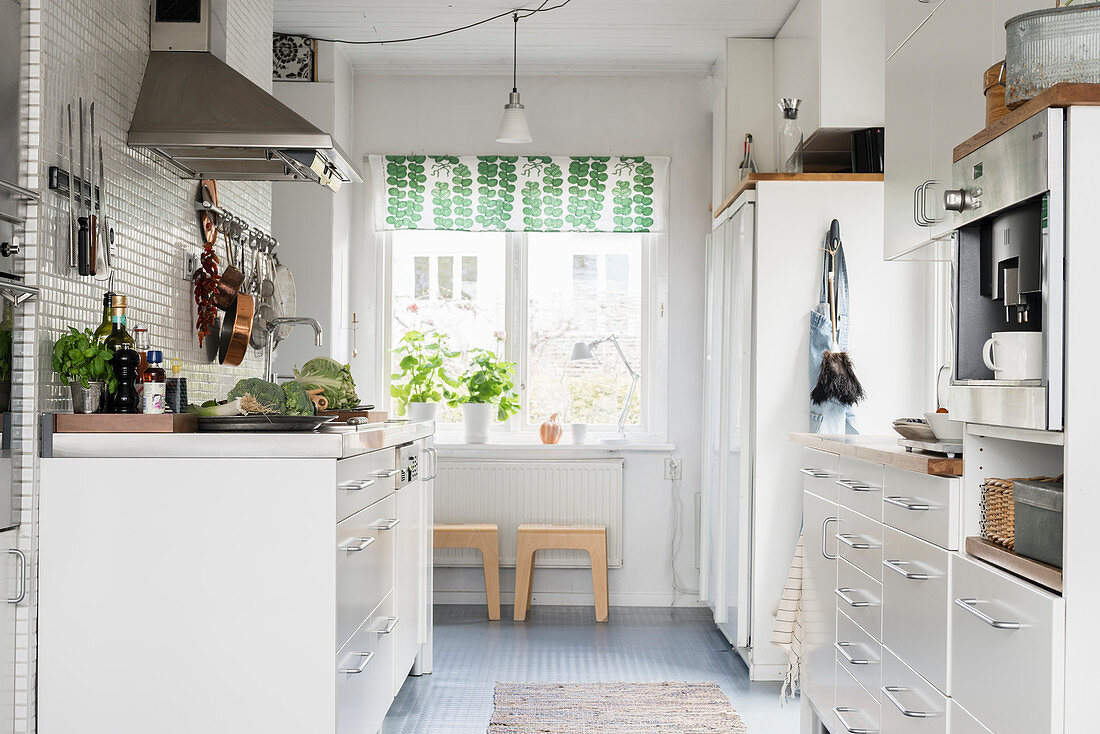 White cupboards in kitchen with window at far end