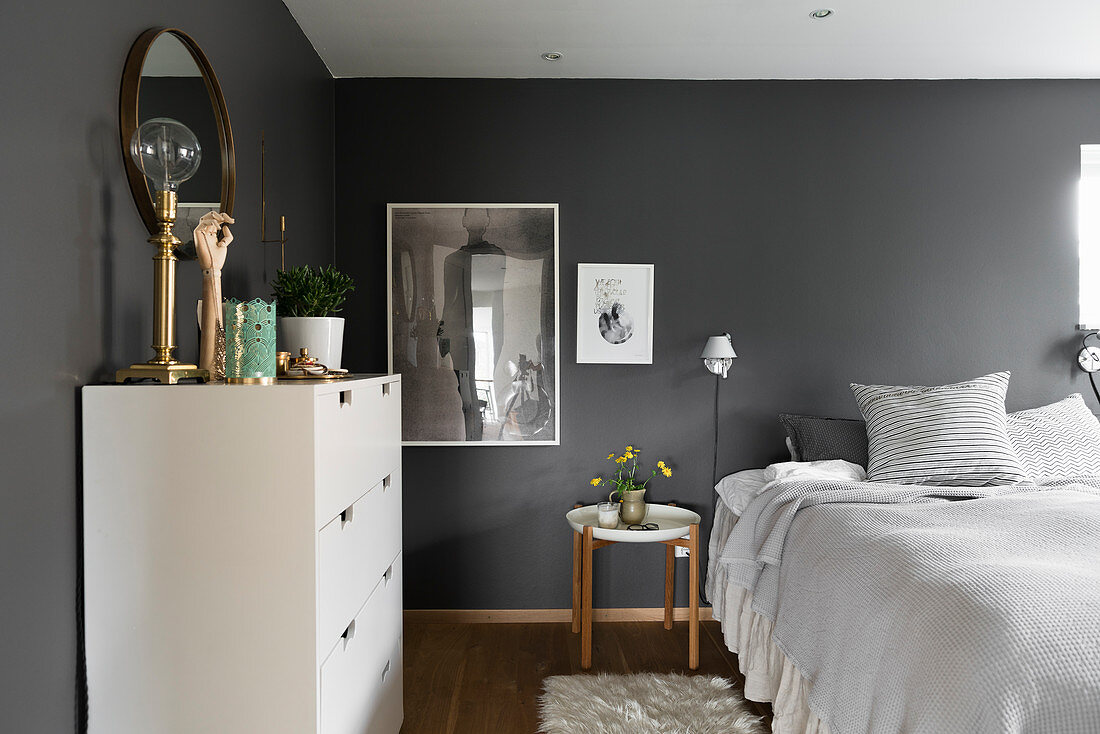 Double bed and white chest of drawers in bedroom with dark grey walls