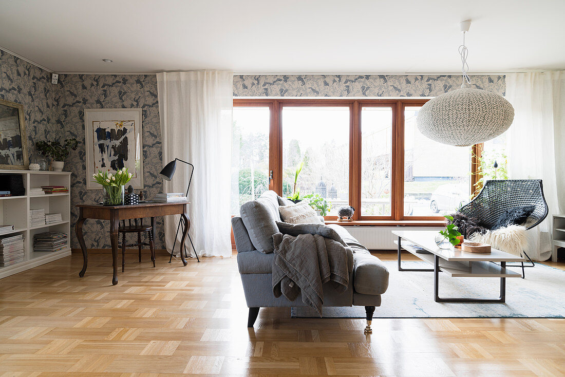 Sofa, coffee table and armchair in front of window and antique desk in corner