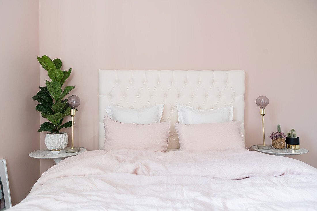 Double bed with white headboard in pale pink bedroom